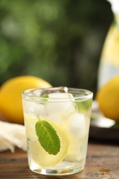 Photo of Cool freshly made lemonade in glass on wooden table