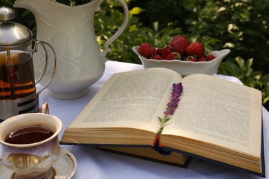 Photo of Books, tea and fresh strawberries on table in garden