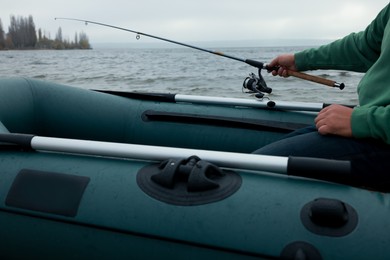 Man fishing with rod from inflatable rubber boat on river, closeup
