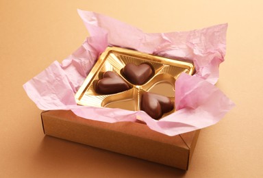 Photo of Partially empty box of chocolate candies on light brown background