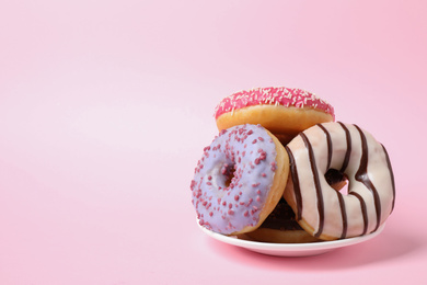 Tasty glazed donuts on pink background, space for text