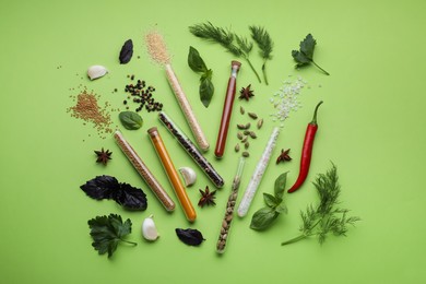 Flat lay composition with various spices, test tubes and fresh herbs on green background