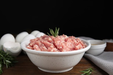 Raw chicken minced meat with rosemary on wooden table