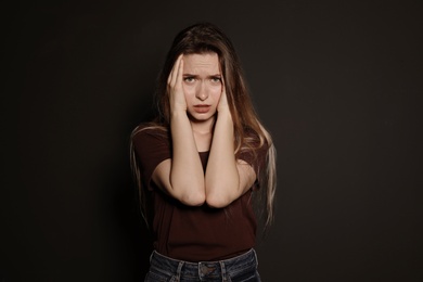 Portrait of upset young woman on dark background