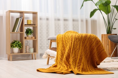 Photo of Spring atmosphere. Wooden bench with blanket, houseplant and shelving unit in stylish room