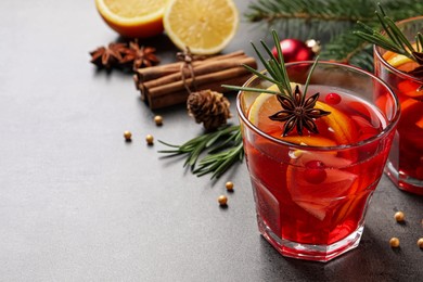 Delicious punch drink with cranberries, orange and spices on grey table. Space for text