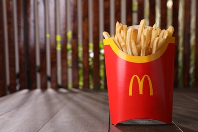 MYKOLAIV, UKRAINE - AUGUST 12, 2021: Big portion of McDonald's French fries on wooden table. Space for text