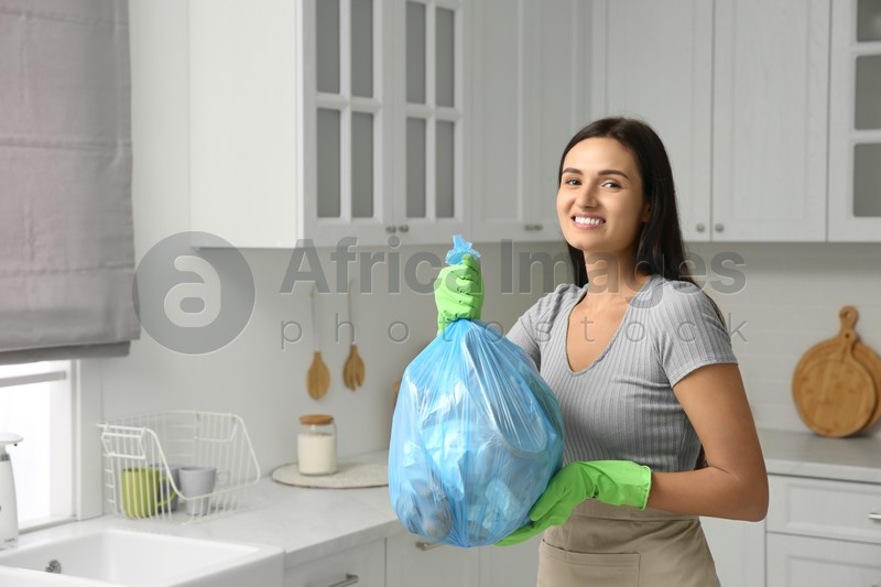 Woman holding full garbage bag at home