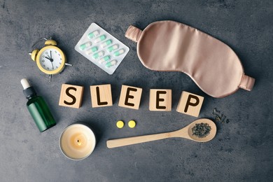 Flat lay composition with word Sleep made of wooden cubes and insomnia remedies on grey background