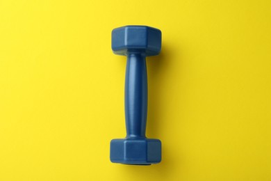 Stylish dumbbell on yellow background, top view
