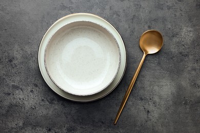 Stylish empty dishware and spoon on grey table, flat lay