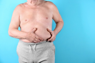 Fat senior man on color background, space for text. Weight loss