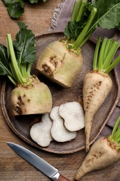 Photo of Whole and cut sugar beets on wooden table, flat lay