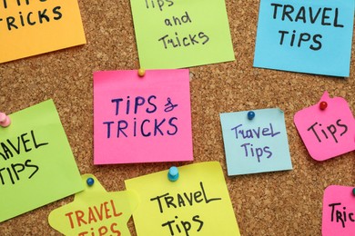 Colorful paper notes pinned to cork board, closeup. Travel tips and tricks