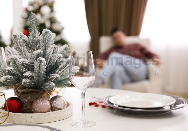 Small Christmas tree, plates and glass on table in room