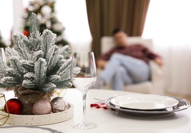 Small Christmas tree, plates and glass on table in room