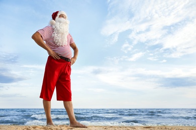 Santa Claus on beach, space for text. Christmas vacation
