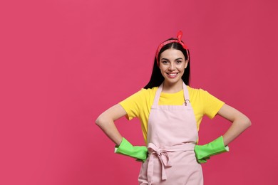 Young housewife wearing rubber gloves on pink background, space for text