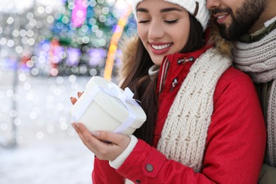 Happy young couple with gift box at winter fair. Christmas celebration