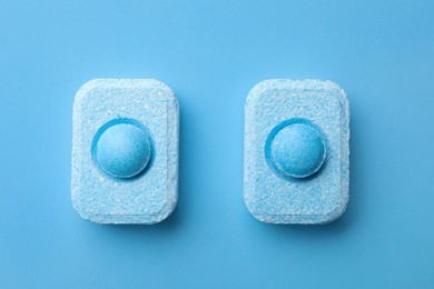 Photo of Water softener tablets on light blue background, flat lay