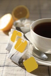 Tea bags near cup of hot drink on table, closeup