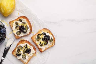Tasty sandwiches with cream cheese, blueberries, blackberries and lemon zest on white marble table, flat lay. Space for text