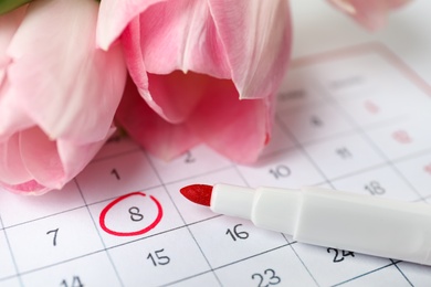 Tulips and red marker on calendar near date 8th of March, closeup. International Women's Day