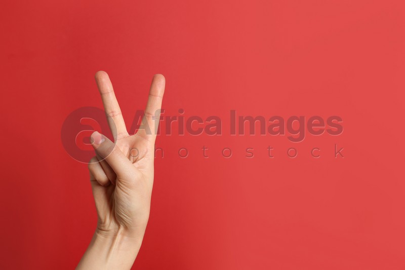 Photo of Woman showing victory sign on color background. Space for text