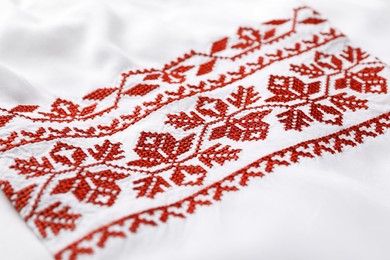 Beautiful red Ukrainian national embroidery on white fabric, closeup