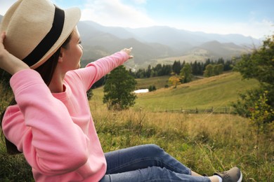 Young woman enjoying beautiful view of mountain landscape. Space for text