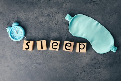 Word Sleep made of wooden cubes near blindfold and alarm clock on grey background, flat lay. Insomnia concept