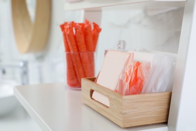 Organizer with tampons and menstrual pads on shelving unit in bathroom. Feminine hygiene products