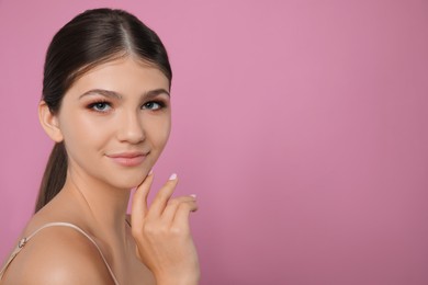 Portrait of pretty girl on pink background, space for text. Beautiful face with perfect smooth skin