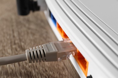 Connected cable to router on wooden table, closeup. Wireless internet communication