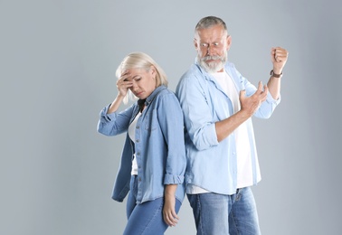 Mature couple having argument on grey background. Relationship problems
