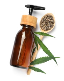 Bottle of hemp cosmetics with green leaves and seeds isolated on white, top view