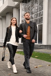 Happy couple wearing stylish leather jackets on city street. Autumn walk