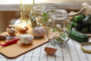 Photo of Empty glass jars and ingredients prepared for canning on table