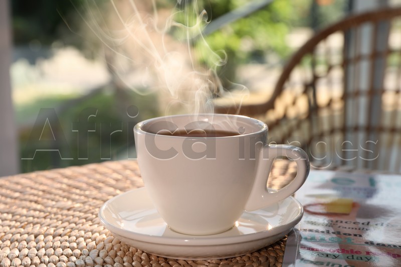 Cup of delicious coffee on rattan table in morning