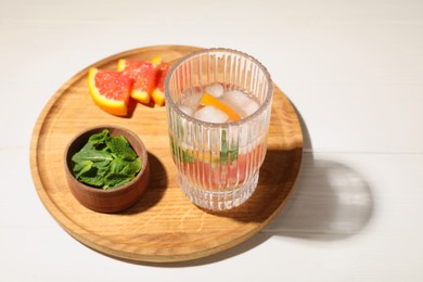 Delicious refreshing drink with sicilian orange and mint near fresh ingredients on white wooden table