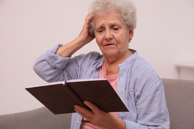 Senior woman with notebook at home. Age-related memory impairment