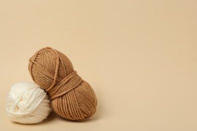 Soft woolen yarns on beige background, space for text