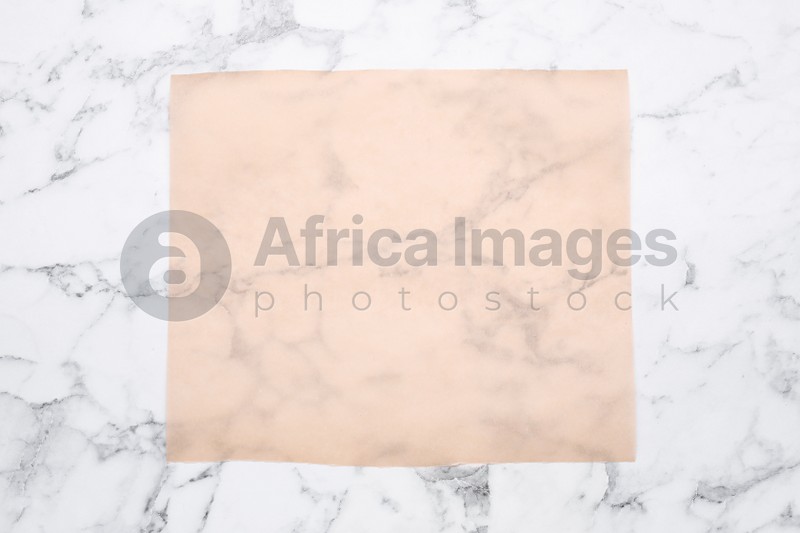 Photo of Sheet of baking paper on white marble table, top view