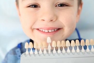 Photo of Selecting cute boy's teeth color with palette in clinic. Visiting dentist
