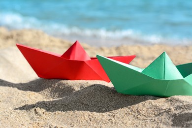 Photo of Two paper boats near sea on sunny day, closeup
