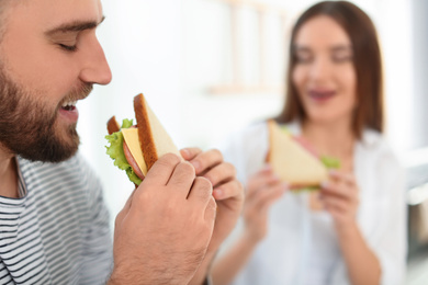 Photo of Happy couple having breakfast with sandwiches at home, closeup. Space for text