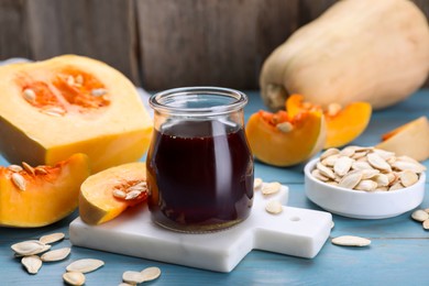 Fresh pumpkin seed oil in glass jar on blue wooden table