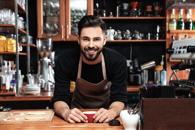 Photo of Portrait of barista with cup of coffee at bar counter