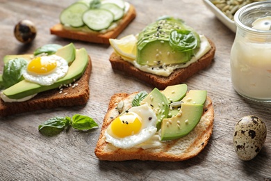 Toast bread with fried eggs, avocado and cucumber slices on wooden table