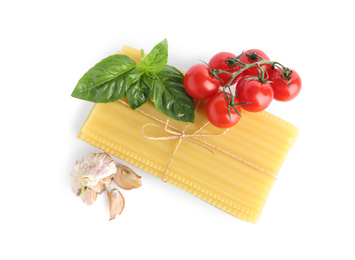 Uncooked lasagna sheets with cherry tomatoes, garlic and basil isolated on white, top view
